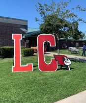 large LC letters on lawn with cardinal mascot